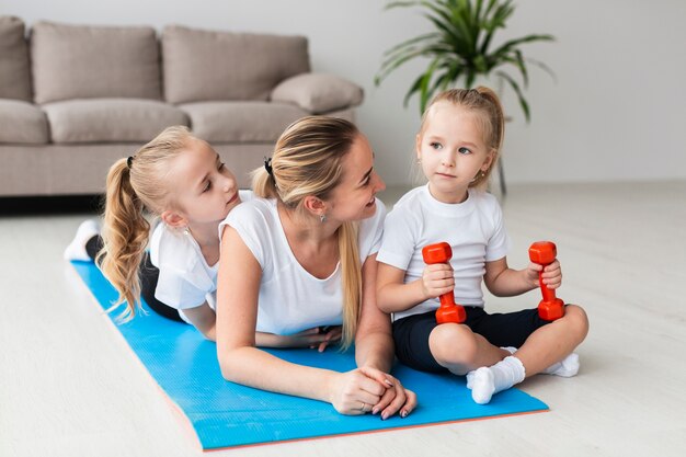 Mother posing with daughters on yoga mat at home