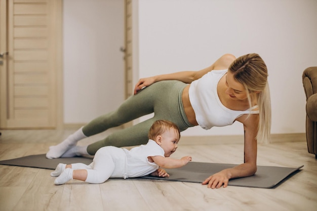 Mother practicing yoga with her baby daughter at home