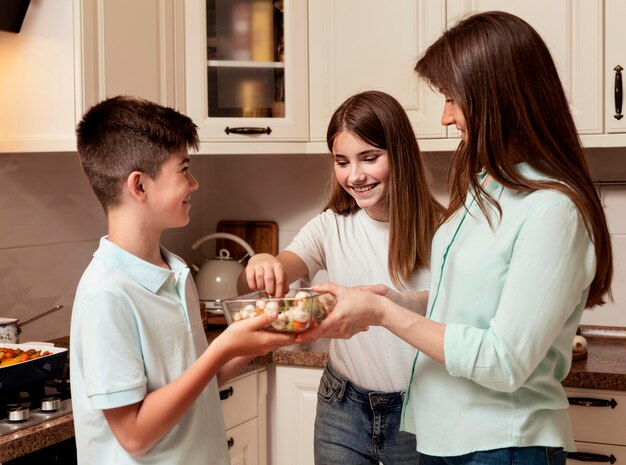 Mother preparing food in the kitchen with children