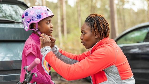 Free photo mother preparing her daughter for a bicycle ride