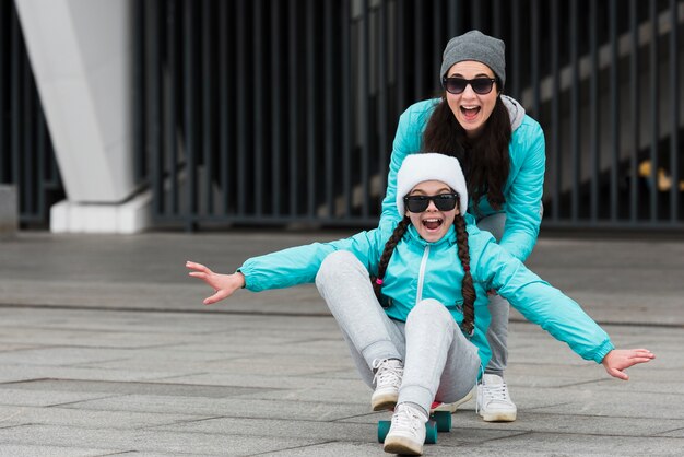 Mother pushing girl on skateboard