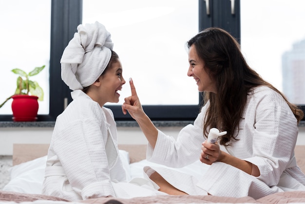 Mother putting skin care cream on her daughters face