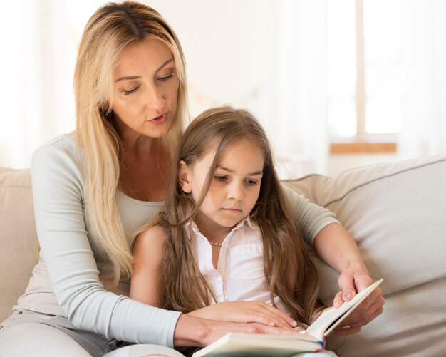 Mother reading book to daughter at home