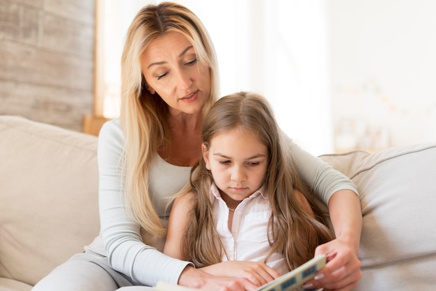 Mother reading from book to daughter at home
