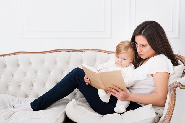 아기와 함께 소파에 독서하는 어머니
