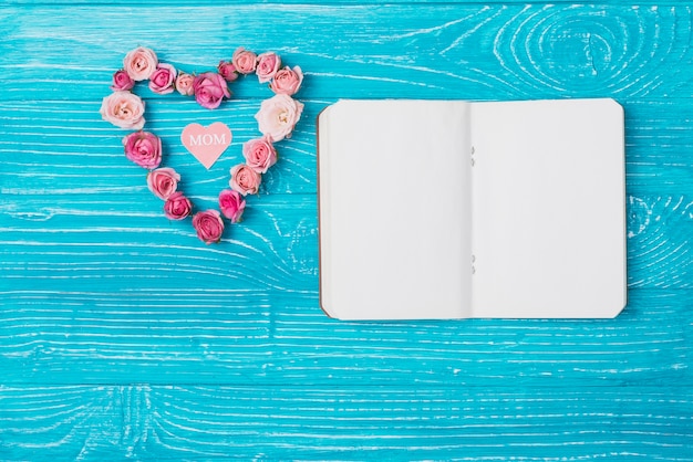 Foto gratuita composizione giorno della mamma con il taccuino in bianco e cuore floreale