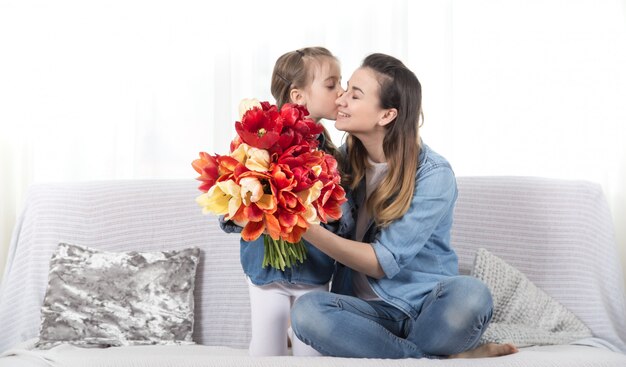 Mother's day. Little daughter with flowers congratulates her mother