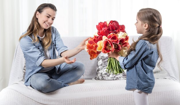 Mother's day. Little daughter with flowers congratulates her mother