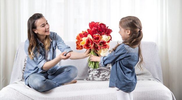 Mother's day. Little daughter with flowers congratulates her mother