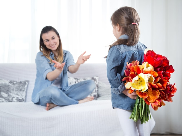 母の日。花を持つ小さな娘は彼女の母親を祝福します