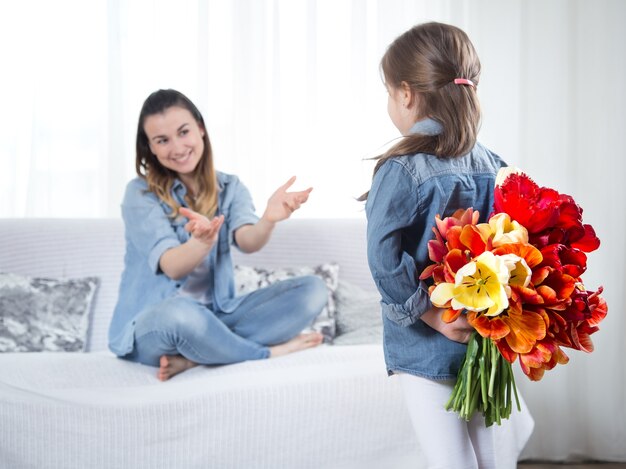 Mother's day. Little daughter with flowers congratulates her mother