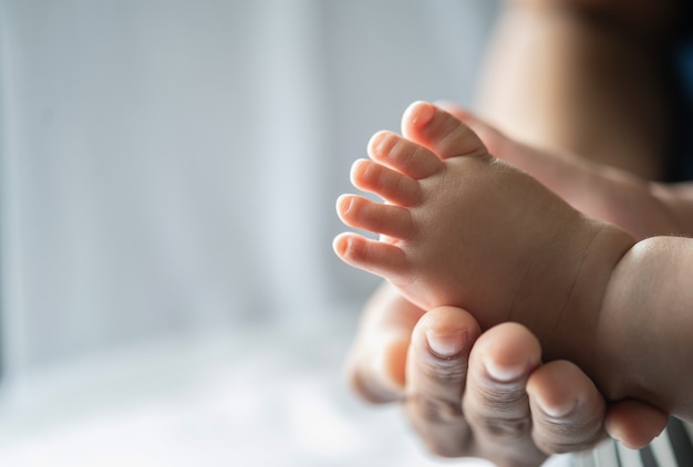 母親の手は新生児の足を優しくしました。