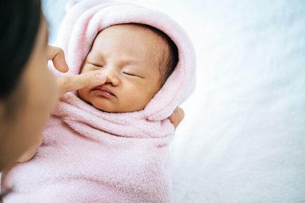 mother's hand touches the nose of the newborn baby