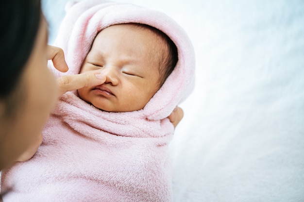 母の手が生まれたばかりの赤ちゃんの鼻に触れる