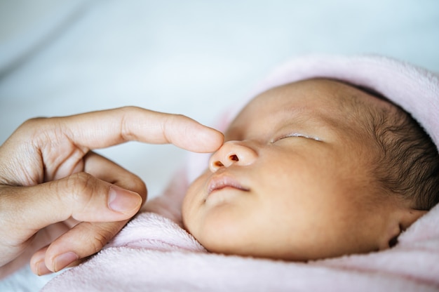 mother's hand touches the nose of the newborn baby