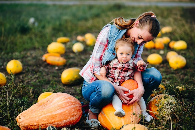 Mother sitting her daughter on a pumpkin