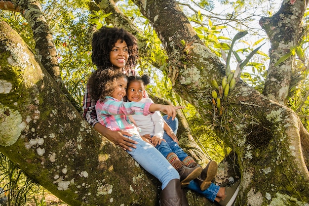 Mother sitting on tree holding daughters