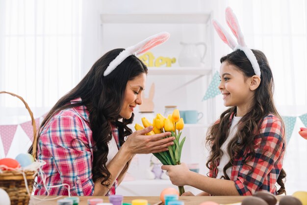 Mother smelling the yellow tulips given by her daughter on easter day celebration