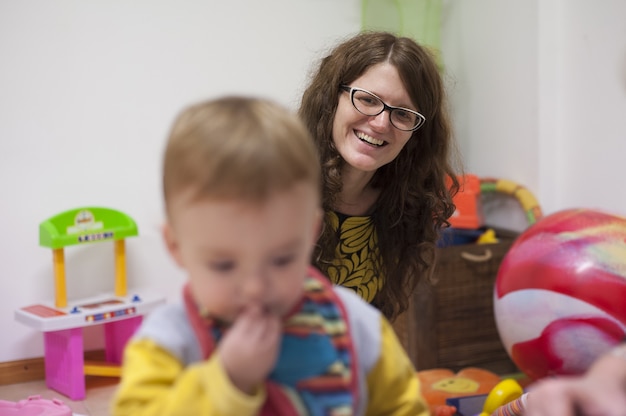 Mother smiles at her child as he plays during an early stimulation session