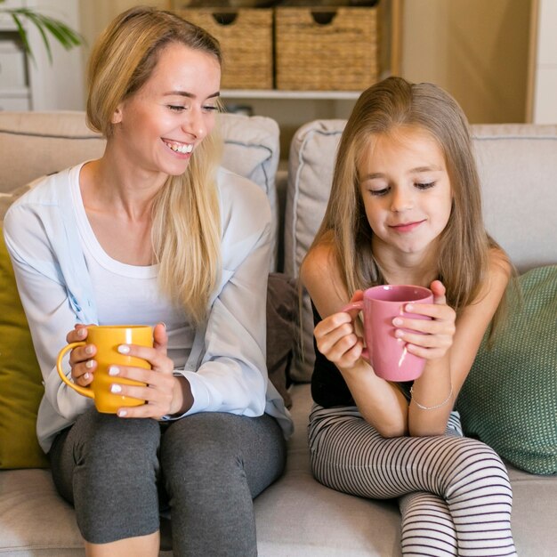 Mother smiling at her child and holding mugs