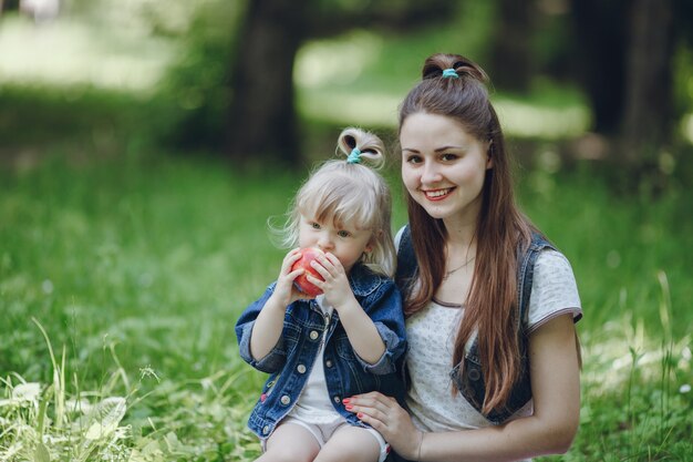 Mother smiling while her daughter eats an apple