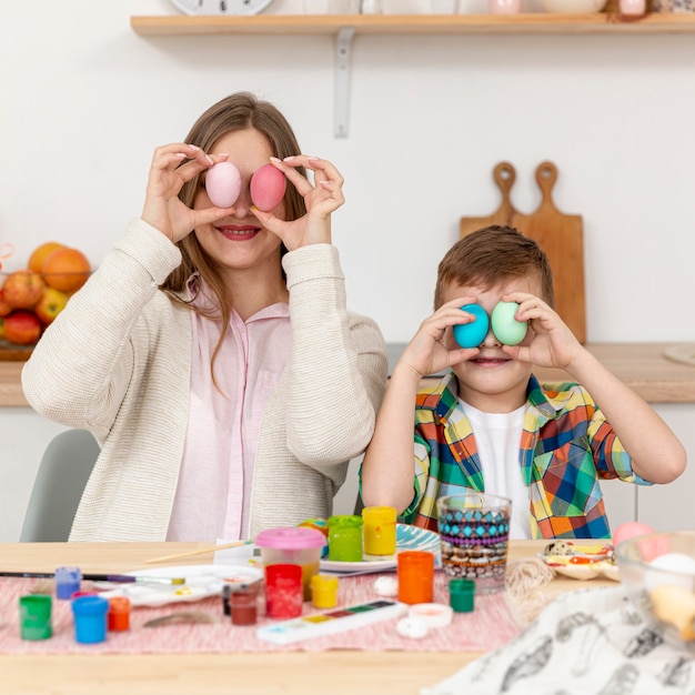 Mother and son covering eyes with painted eggs