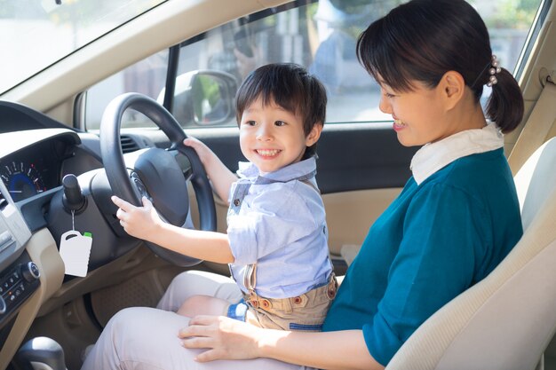 Mother and son enjoy to play with the steering wheel of car