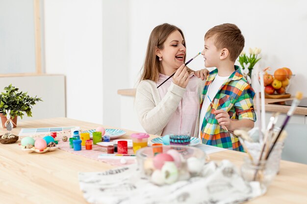 Mother and son having fun while painting eggs