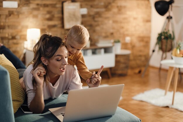 Mother and son having fun while using computer in the living room