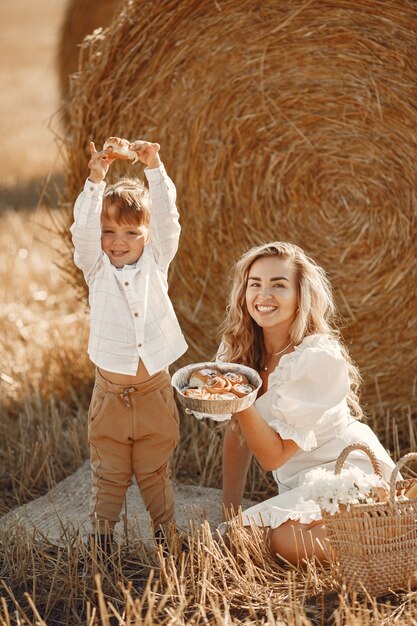 Mother and son. Hay stack or bale on yellow wheat field in summer. Children having fun together.