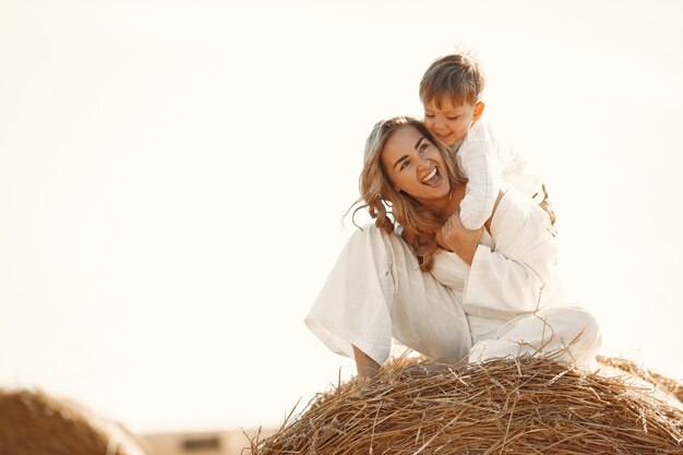 Mother and son. Hay stack or bale on yellow wheat field in summer. Children having fun together.