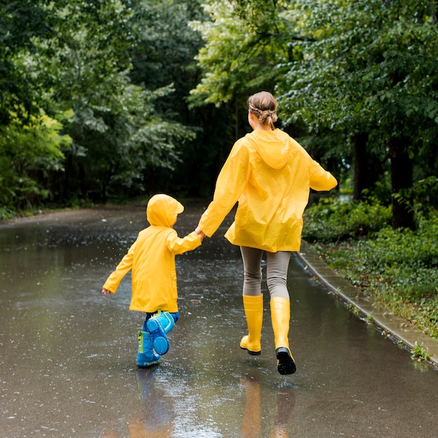 Mother and son holding hands while wearing rain coats