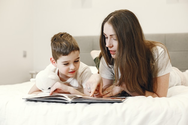 Mother and son lying on the bed reading a book.