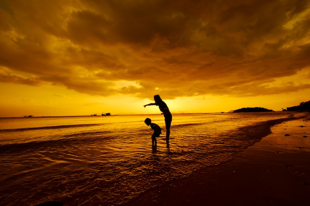 Free photo a mother and son in outdoors at sunset with copy space