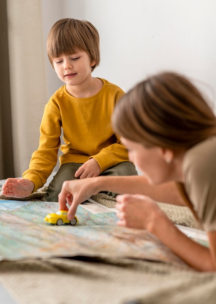 Madre e figlio che giocano insieme con la figurina dell'auto e la mappa