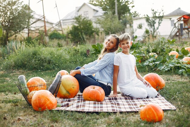 Mother and son  sitting on a garden near many pumpkins
