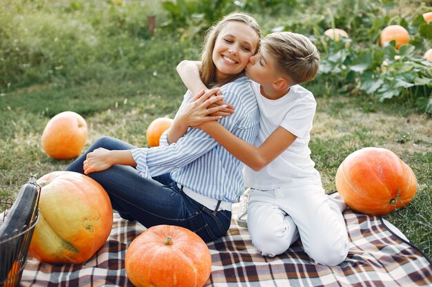 Mother and son  sitting on a garden near many pumpkins