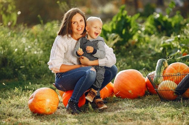 Mother and son sitting on a garden near many pumpkins