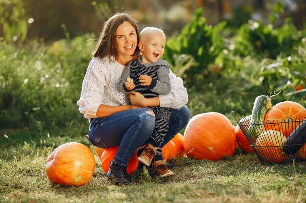 Mother and son sitting on a garden near many pumpkins