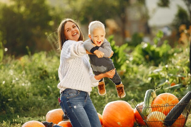 Mother and son sitting on a garden near many pumpkins