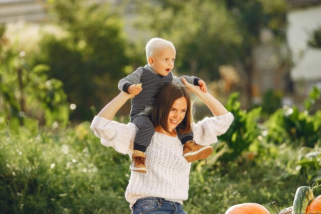 Mother and son sitting on a garden near many pumpkins