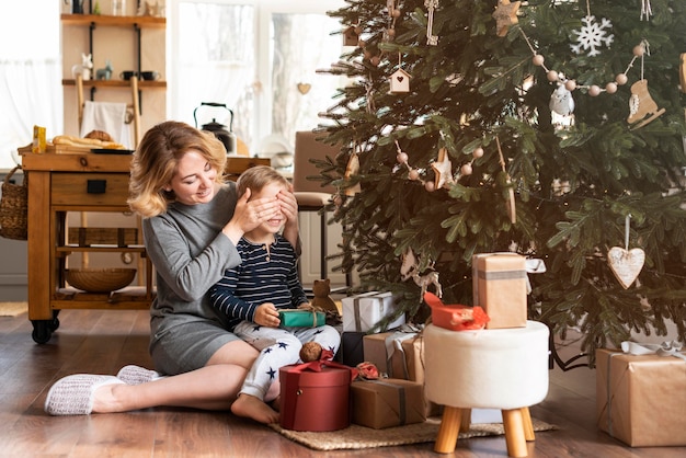 Mother surprising boy with gift with copy space