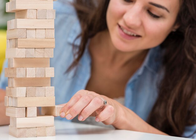 Mother taking care while getting a piece of a wooden tower game