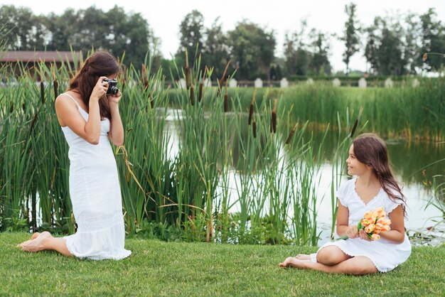 Mother taking photo of daughter by the lake