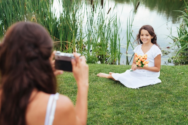 Mother taking photo of daughter by the lake