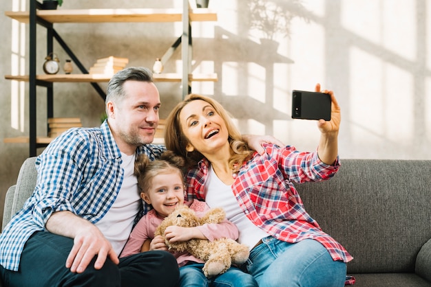 Mother taking selfie of cell phone with her father and daughter