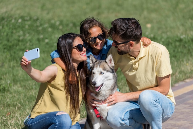 Mother taking a selfie of family with dog at the park