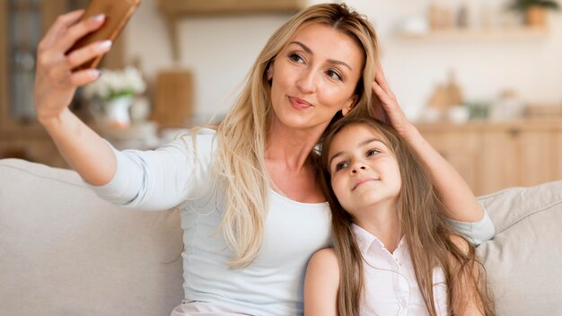 Mother taking selfie with daughter at home