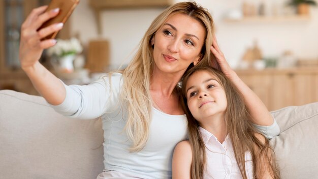 mother taking selfie with daughter at home