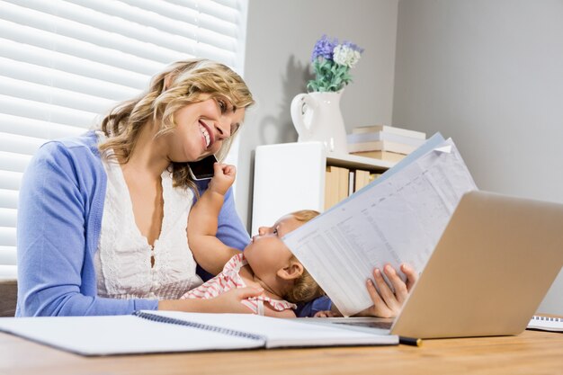 Mother talking on mobile phone while holding her baby girl